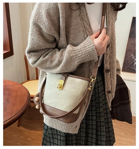 Detail of vintage bucket bag featuring brown leather trim and golden metal lock clasp