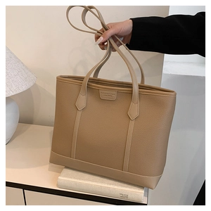 Detalle del bolso tote de cuero caqui con logotipo en relieve y textura de grano de cuero