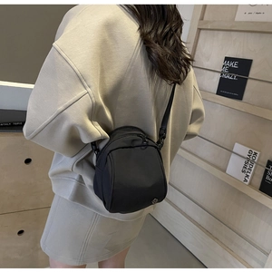 Dettaglio della borsa a tracolla nera minimalista in nylon con tracolla regolabile e forma a mezzaluna