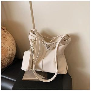 Detail of off-white faux leather tote bag featuring vertical stitching and a mini ear charm