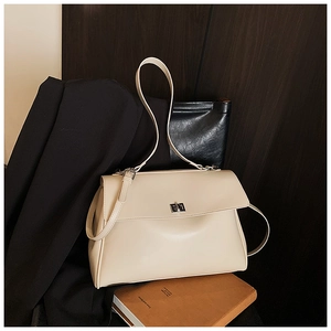 Close-up of cream leather briefcase featuring a silver rotating clasp and minimalist texture