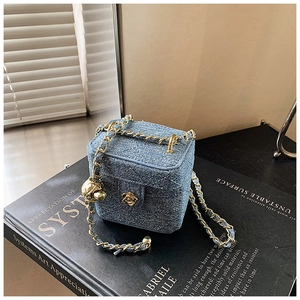 Detail of blue denim mini box bag with quilted pattern and golden camellia lock