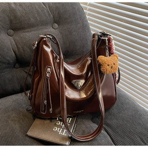 Detailaufnahme der dunkelbraunen Ölwachs-Ledertasche mit Kontrastnaht und Bär-Anhänger