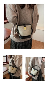 Detailed close-up of a stylish bucket bag with gold lock and brown plush charm accessory