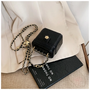 Close-up of black quilted mini bag featuring golden floral buckle and chain strap