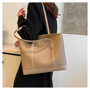 Detalle del bolso tote de cuero con grano de lichi y etiqueta de marca de moda