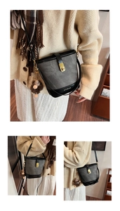 Detail of grey bucket bag with black leather trim, gold lock, and plush bear charm