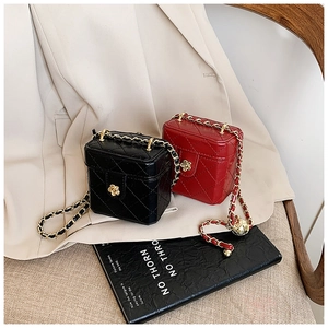 Detail view of mini quilted box bags in red and black with flower locks and chain straps