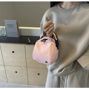 Dettaglio della borsa in nylon rosa con logo rotondo in metallo e cerniera nera