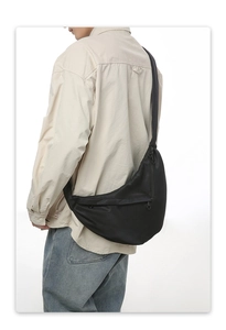 Detail view of the black crescent crossbody bag showing matte nylon fabric and strap