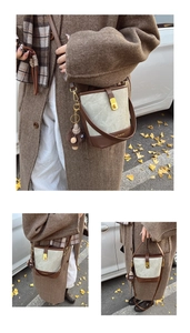 Detail of color-block bucket bag with gold lock and plush charm on autumn street