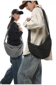 Front view of black and grey crescent nylon crossbody bags worn by models in studio