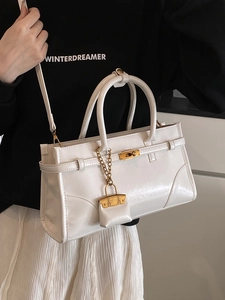 Glossy white retro briefcase style handbag with metallic lock and mini charm accessory