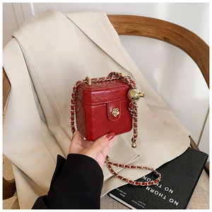 Detail of red quilted mini bag featuring golden camellia clasp and adjustable chain strap
