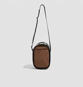 Rear view of brown nylon crossbody phone bag showing the open back pocket and strap