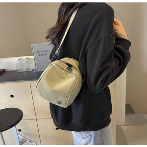 Dettaglio ravvicinato di una borsa a tracolla in nylon kaki chiaro con logo in metallo