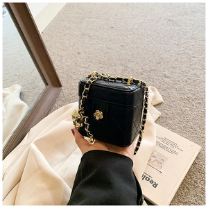Detail of a mini quilted black box bag with golden skull charm and chain strap