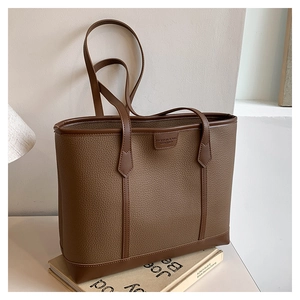 Detalle de bolso tote grande de piel marrón con esquinas reforzadas y asa de hombro