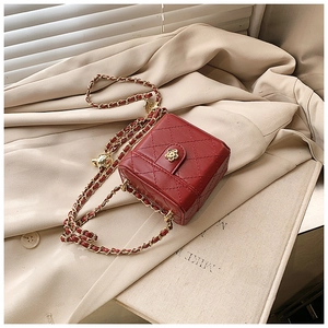 Detailed close-up of a red quilted leather mini box bag with gold flower clasp