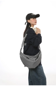 Detailed view of a grey waterproof nylon crossbody bag styled with casual streetwear outfit