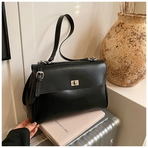 Detail of classic black leather satchel bag with silver twist lock on a suitcase
