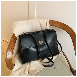 Detail of black leather briefcase bag with metal clasp on a vintage wooden chair