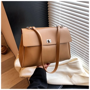 Close-up of a tan leather commuter briefcase with silver square twist lock and shoulder strap