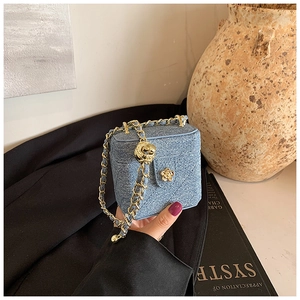 Detailed view of mini blue denim bag with golden camellia buckle and chain strap