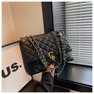 Detailed view of black quilted leather shoulder bag with golden chain and twist lock