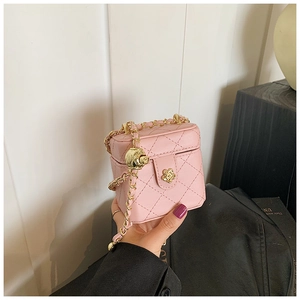 Detail of pink quilted mini box bag with golden floral lock and chain strap