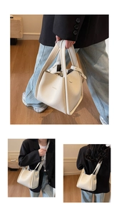 Detail view of cream white lychee grain leather bucket bag with brand logo and stitching