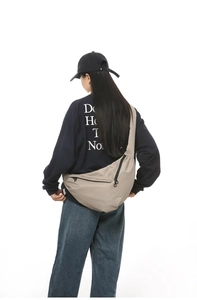 Detail of khaki crescent crossbody bag with multi-pocket zipper and adjustable nylon strap