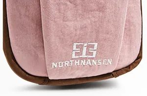 Detail of the pink utility crossbody bag with embroidered logo and contrast brown edging