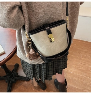 Detail of grey canvas bucket bag with black leather trim and a cute teddy bear charm