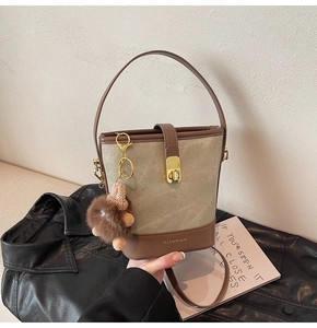 Detail of canvas bucket bag with brown leather trim and plush animal charm decoration