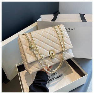 Close-up of cream quilted handbag featuring gold twist lock and leather woven chain strap