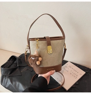 Detail of olive green contrast bucket bag with gold buckle and plush monster charm