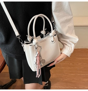 Detail of white PU leather bucket bag featuring a woven rope handle and crossbody strap