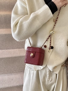 Burgundy quilted mini chain box bag with golden camellia buckle worn as a crossbody