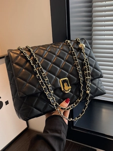 Quilted black shoulder bag with gold chain strap and turn-lock closure in modern interior