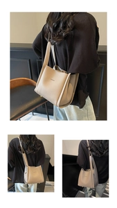 Detail view of beige lychee textured bucket bag featuring slim straps and metallic feet