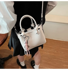 White oil wax leather bucket bag worn by model in a cozy cafe setting with crossbody strap