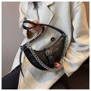 Detail of black crocodile texture handbag with chunky silver chain and buckle detail