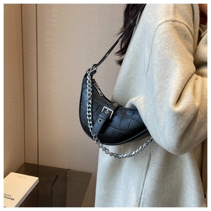 Detail of black crocodile texture half-moon bag with silver chain and leather strap