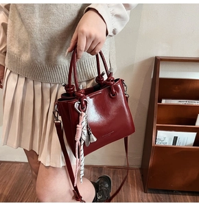 Close-up of vintage burgundy bucket bag with knotted handle and elegant tassel detail