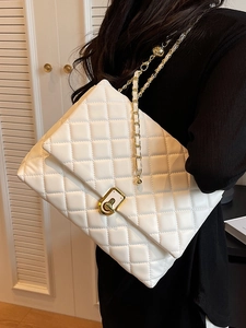 Elegant white quilted crossbody bag with gold chain strap shown on a model