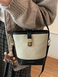 Chic two-tone bucket bag in cream fabric and black leather trim for elegant women