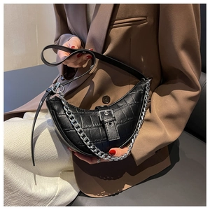 Detail of black faux crocodile leather shoulder bag with bold silver chain and buckle strap