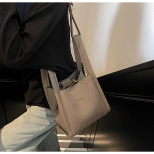 Detail of grey lychee leather bucket bag with brand logo and premium handle texture