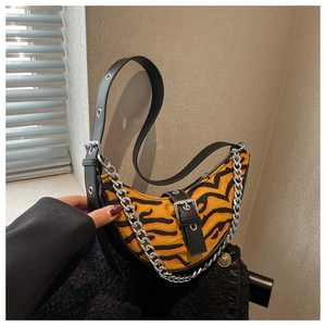 Detail of tiger print crescent bag with silver chain strap and metal eyelet accents